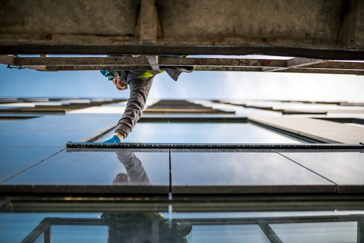 Person Wiping The Glass Window Of A Building 