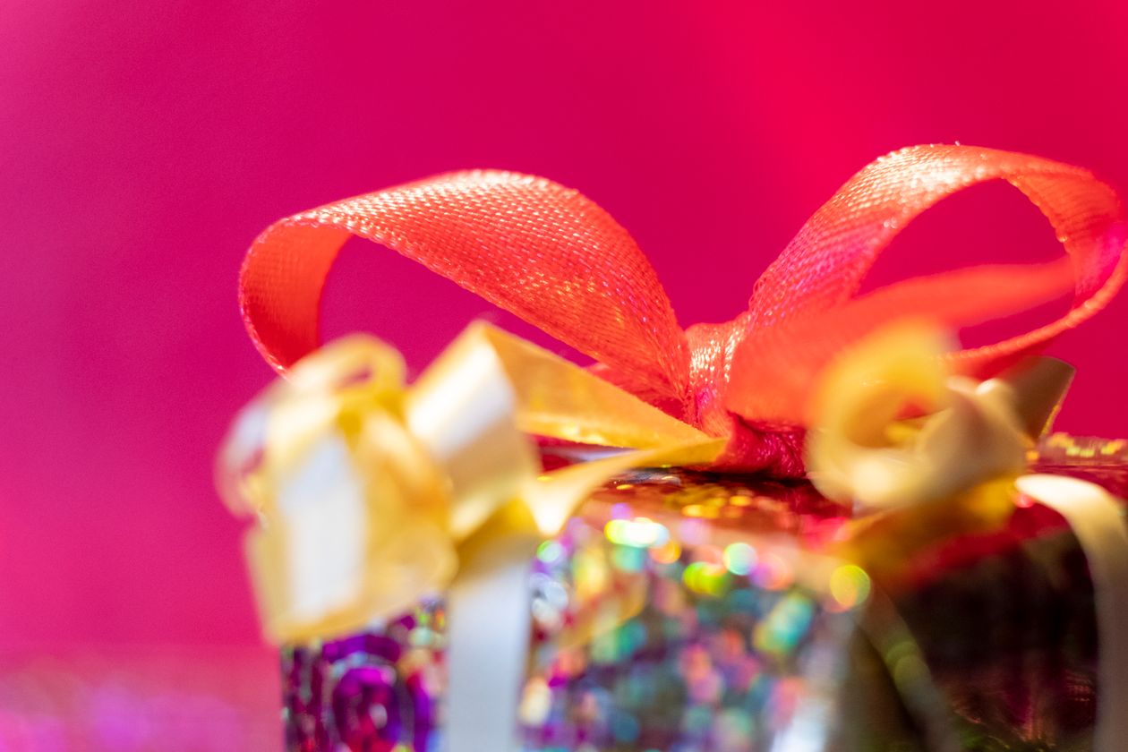 Gift box with colorful ribbons on a pink background representing referral rewards that work