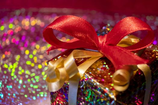 Sparkling gift box wrapped in holographic paper with a red ribbon for special occasions.