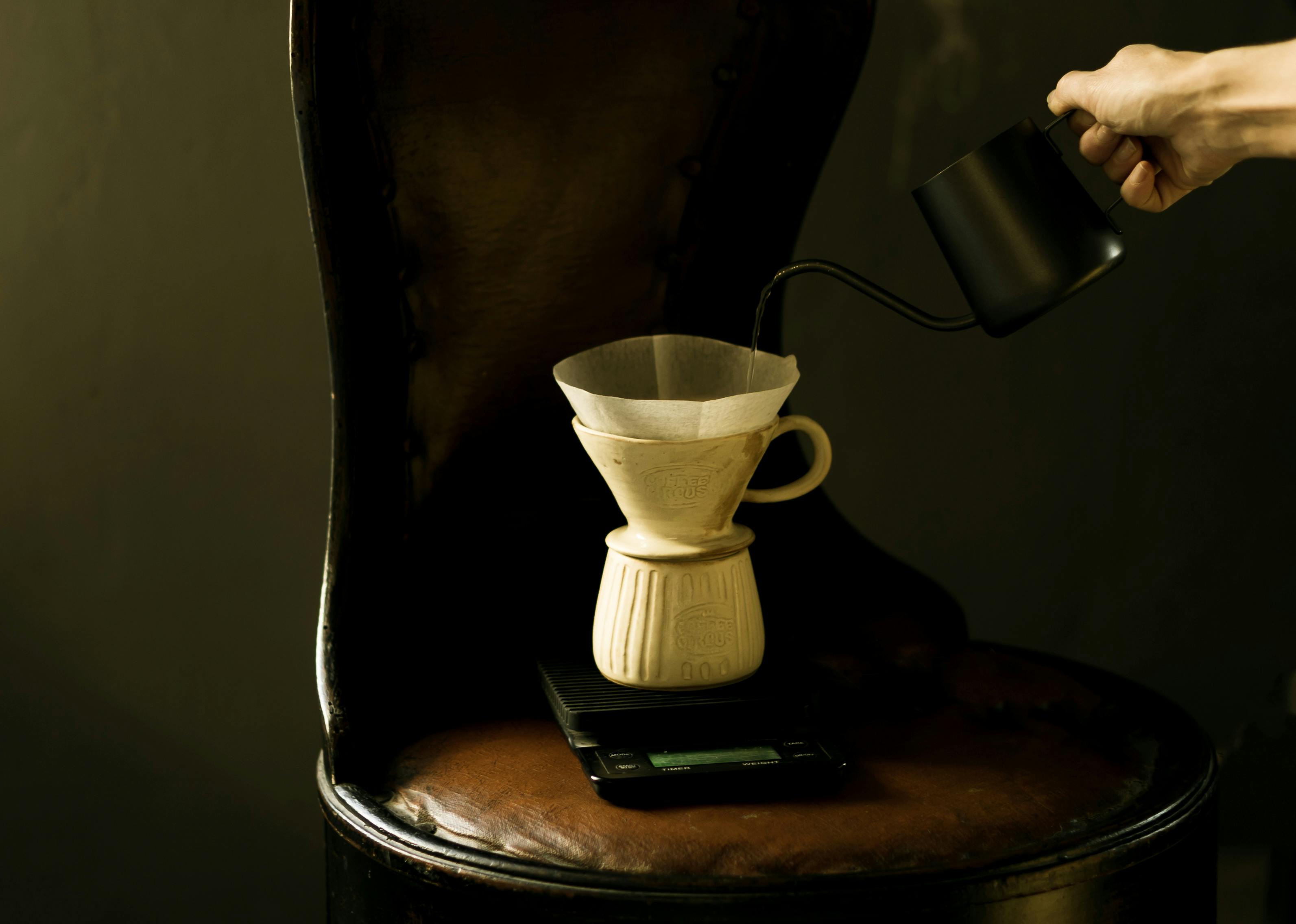 Elegant pour over coffee being made with a dripper on a sophisticated wooden chair.