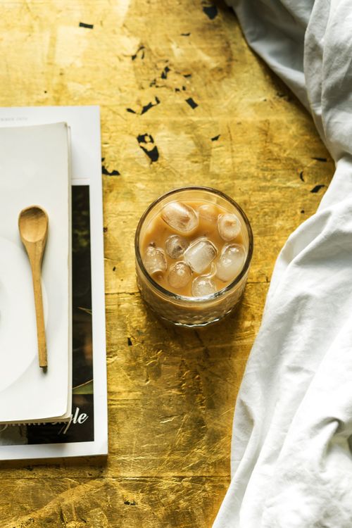 Free A refreshing iced coffee in a glass with a wooden spoon on a rustic table setting. Stock Photo