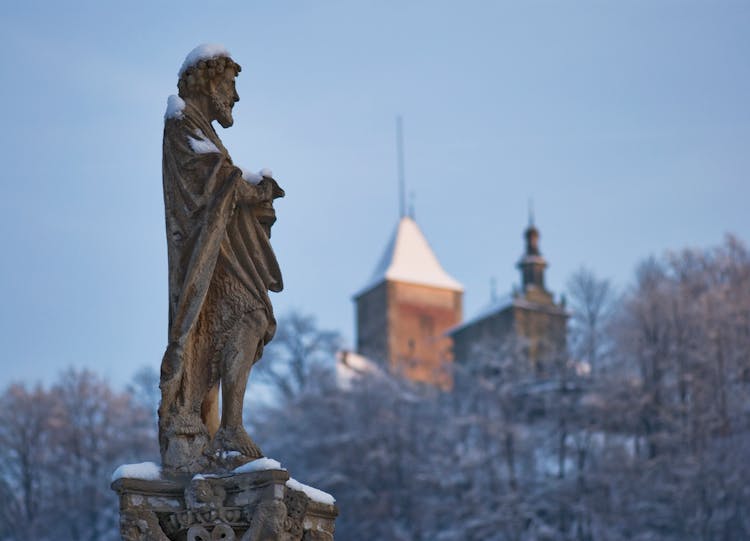 Stone Statue In Snow On City Background