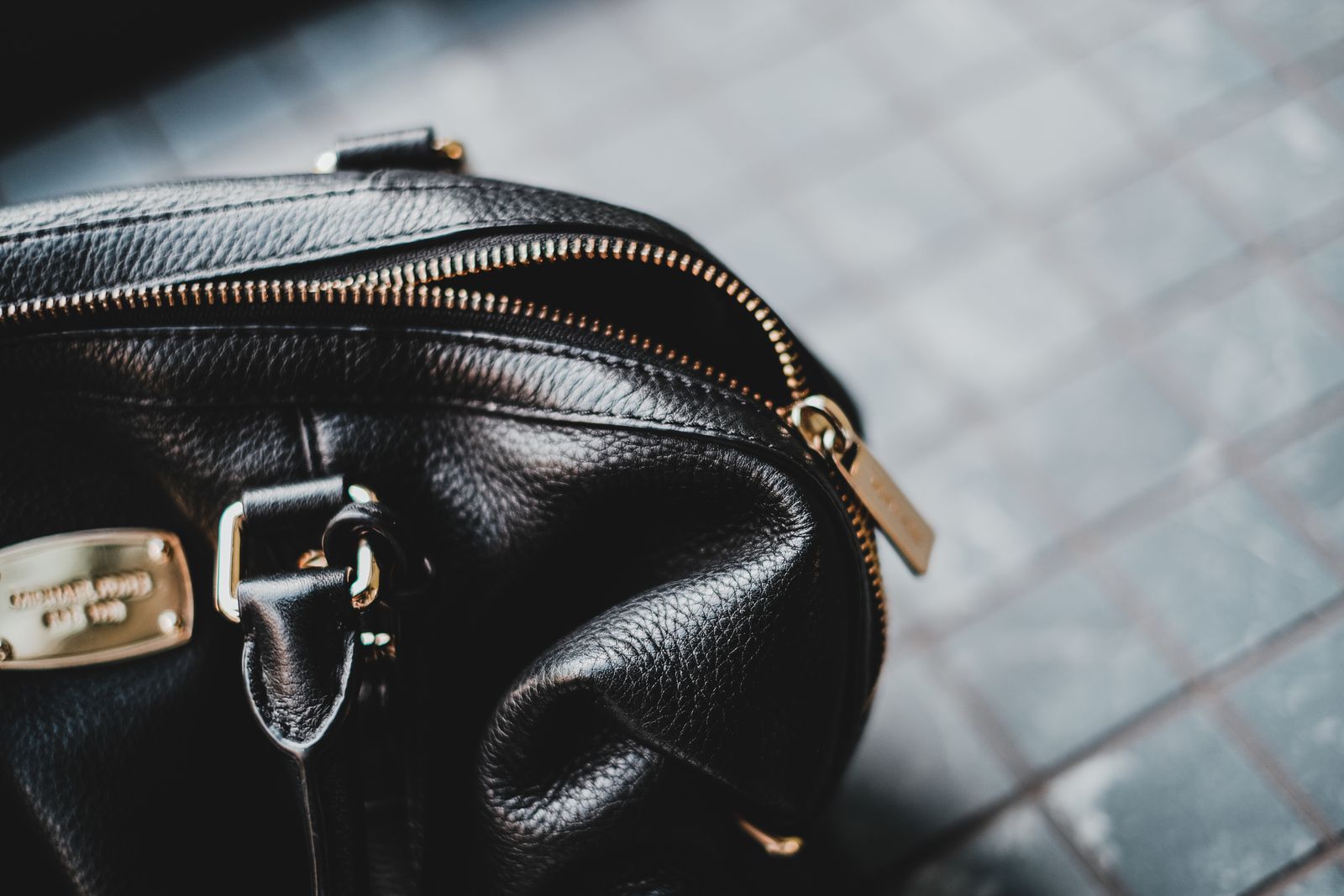 Close-up of a leather bag zipper pull and gold-toned hardware, the kind of detail buyers inspect and approve at the sampling stage.