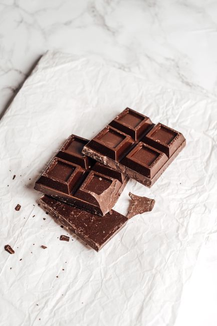 A dark brown bar of German's sweet chocolate broken into squares next to a mixing bowl and shredded coconut for cake frosting