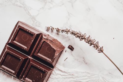 Free Artistic shot of dark chocolate and lavender on a marble background, emphasizing luxury and gourmet appeal. Stock Photo