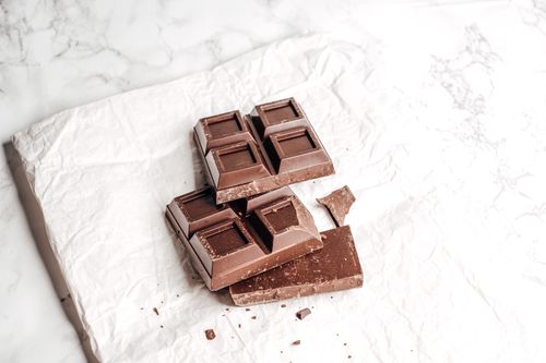 Free Close-up of dark chocolate bar on crumpled white paper, showcasing texture. Stock Photo
