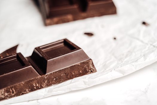 A close-up view of a dark chocolate bar placed on a crumpled wrapper, perfect for food-themed projects.