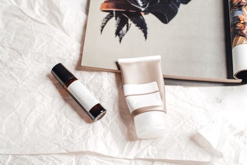 Free Flat lay of skincare products on textured paper with an open magazine, showcasing a stylish aesthetic. Stock Photo