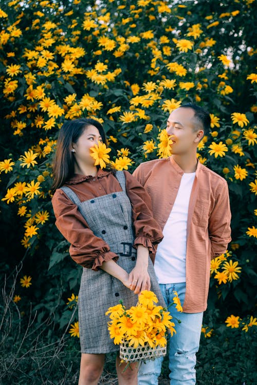 Happy Asian couple with flowers in mouths