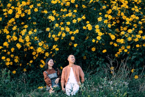 Cheerful Asian couple sitting on grass