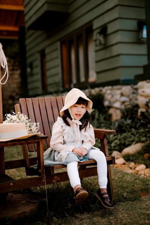 Cute Asian girl sitting on wooden armchair on terrace