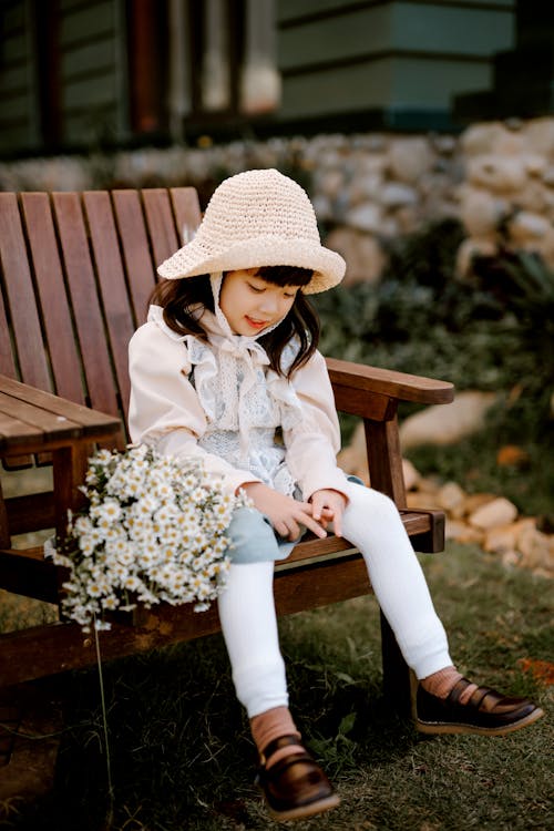 Cute Asian girl sitting on wooden bench