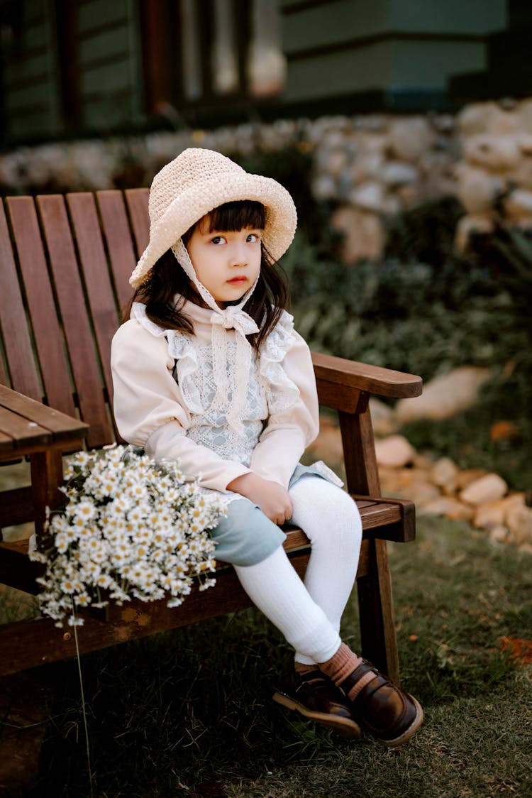 Calm Asian Girl Sitting On Armchair In Backyard