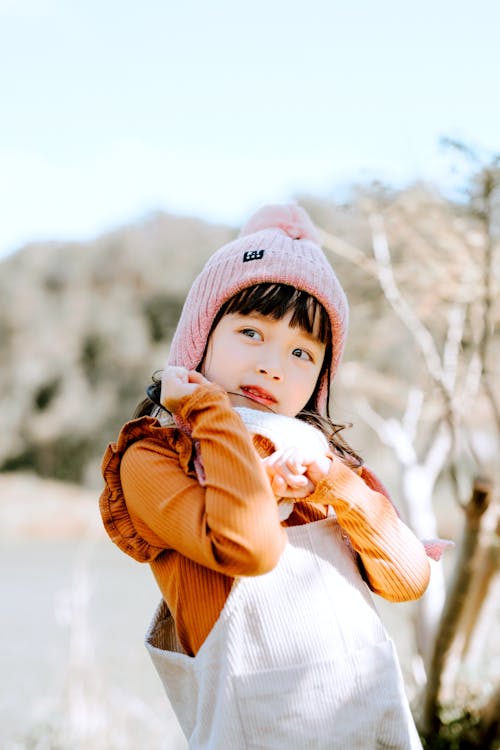 Free Cute Asian girl in hat standing in countryside Stock Photo