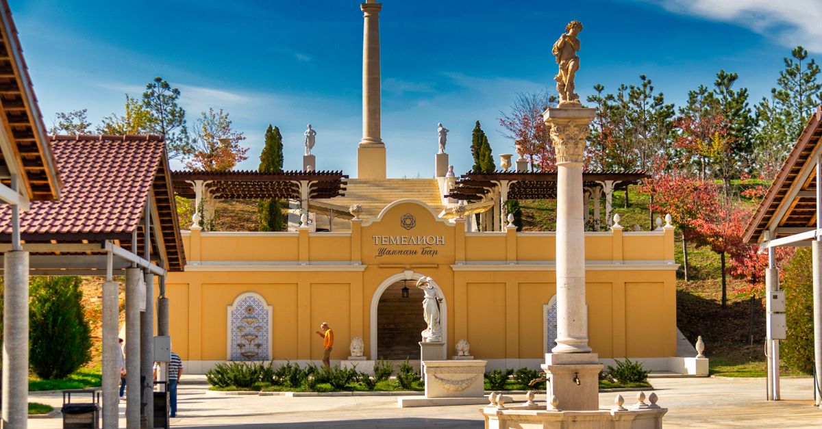 Beautiful historic courtyard featuring classical sculptures and columns under a clear blue sky.