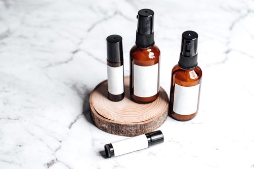 Free Stylish arrangement of amber skincare bottles on marble with wooden accent. Stock Photo