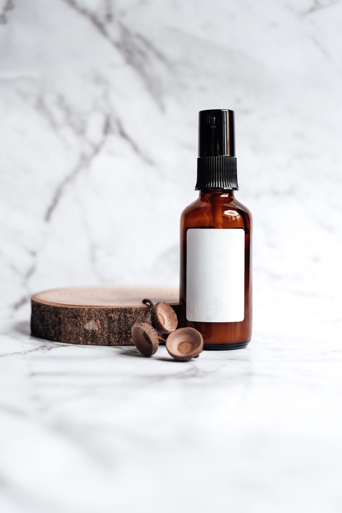 Amber glass spray bottle on a light marble surface with natural wood accents
