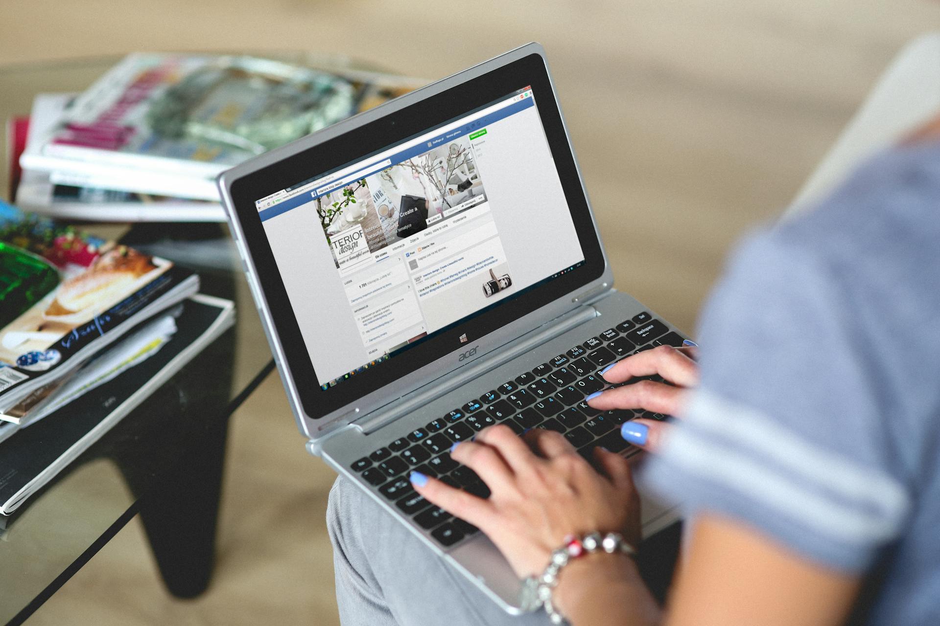 A woman typing on a laptop with social media on the screen, indoors setting.