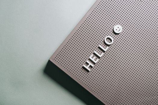 A close-up of a perforated board displaying the text 'HELLO' and a smiley face in a minimalist design.