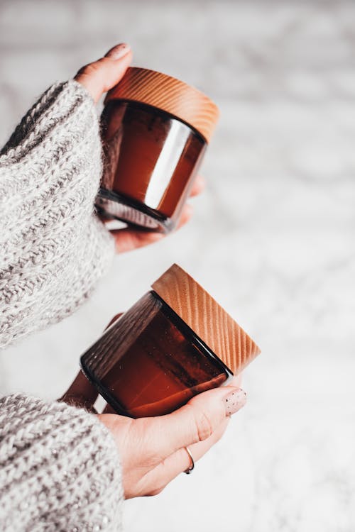 Free Person Holding Brown Glass Jars with Wooden Lids  Stock Photo