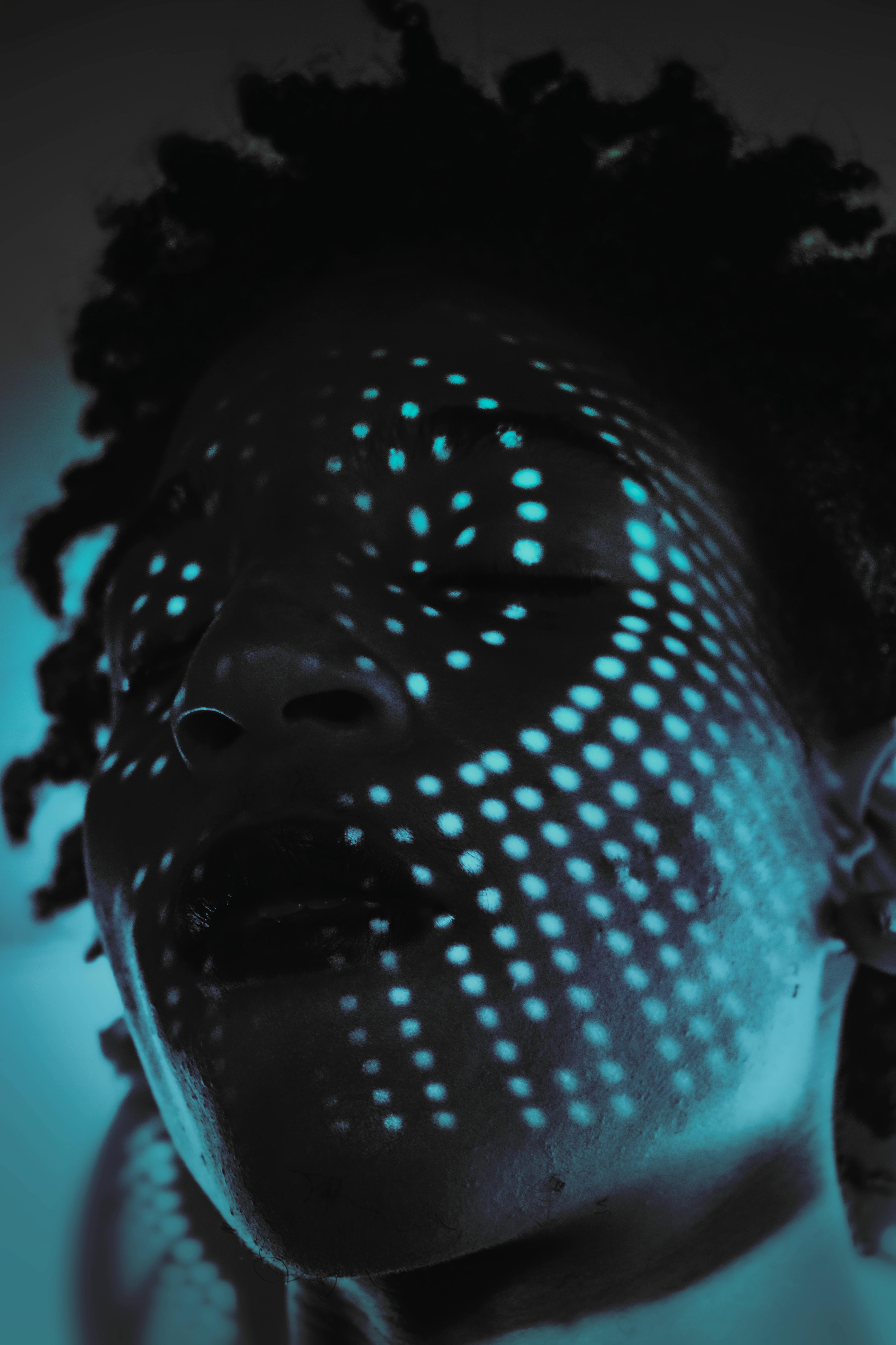 Close-up of a person with creative dot light patterns on face.