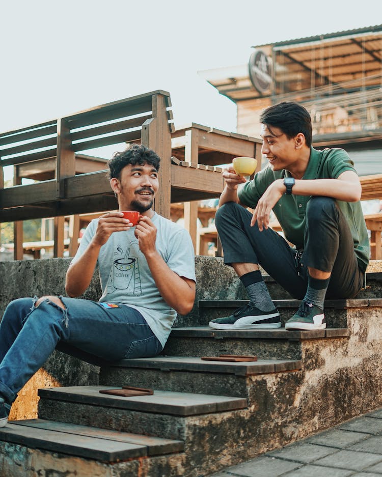 Asian Men Sitting On Stairs With Drinks