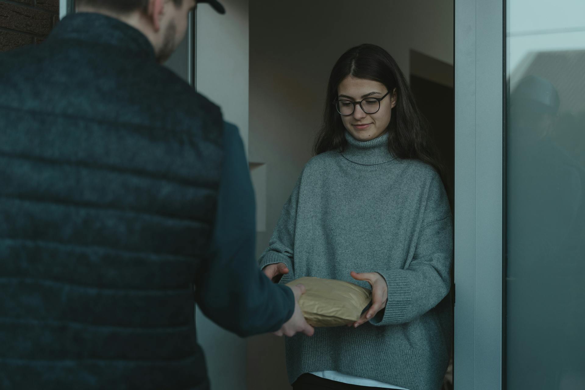 Woman in Gray Sweater receiving a Parcel