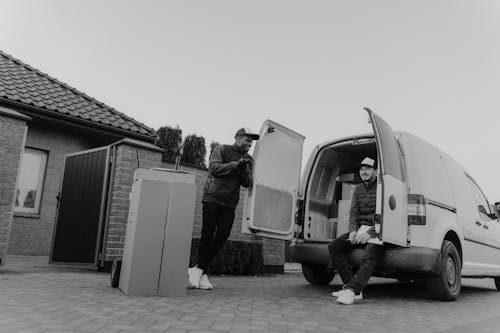 Free Grayscale Photo of Man in Jacket Standing Beside Van Stock Photo