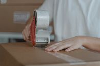 Person putting Tape on a Cardboard