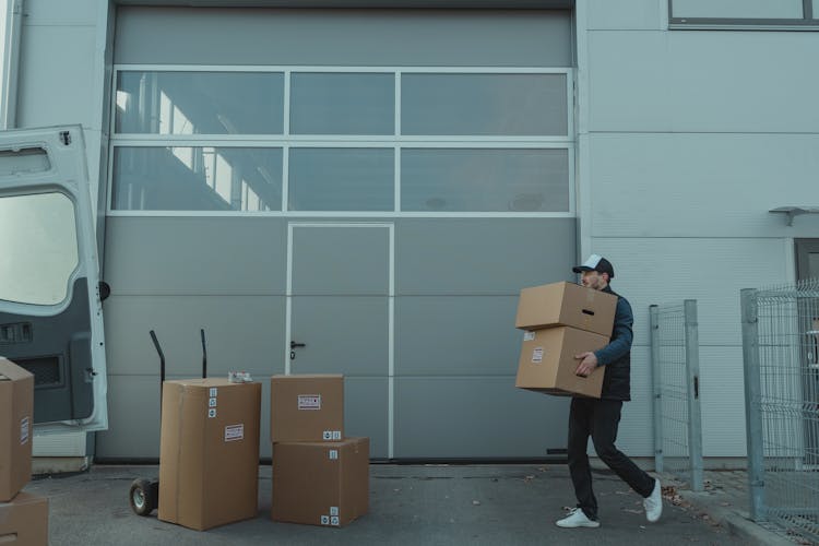 Man Walking While Carrying Brown Cardboard Boxes