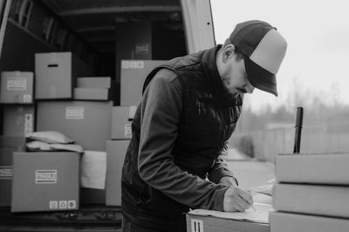 Delivery Man writing on a Carton Box 