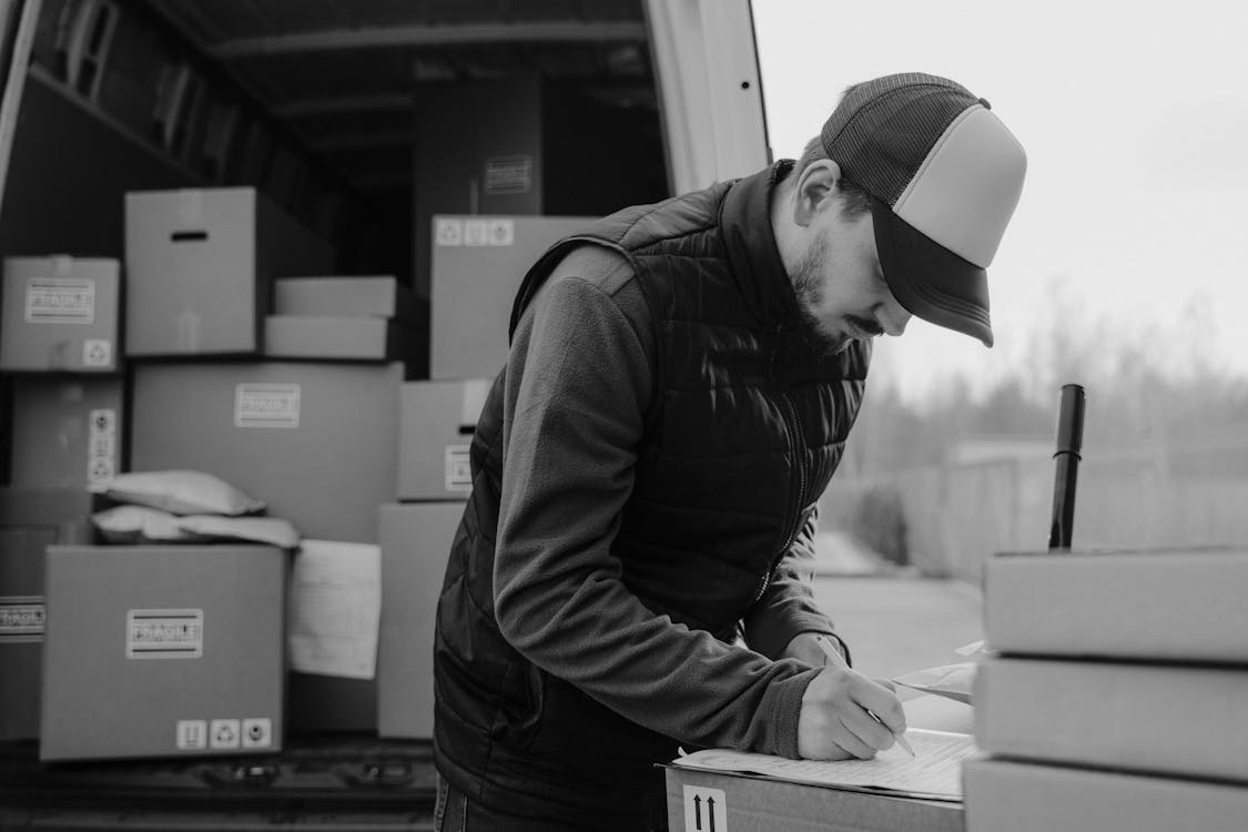 Delivery Man writing on a Carton Box 