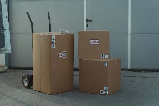 Three cardboard boxes on a dolly, ready for shipping outside a warehouse.