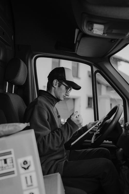 Monochrome Photo of Delivery Man writing on a Paper