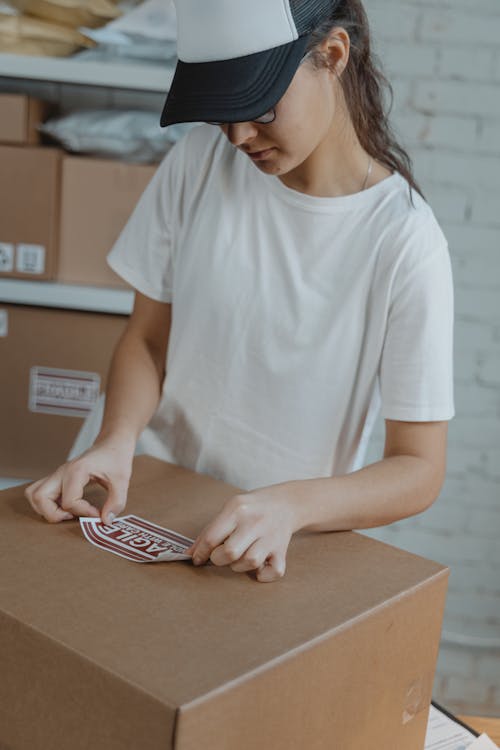 Free Female Employee putting Warning Sticker on a Cardboard  Stock Photo