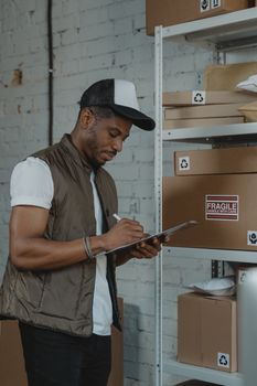 A young employee organizing shipping boxes in a warehouse.
