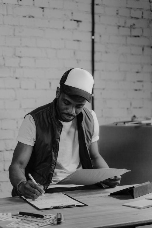 Free Monochrome photograph of a man writing at a desk, focusing on tasks. Stock Photo