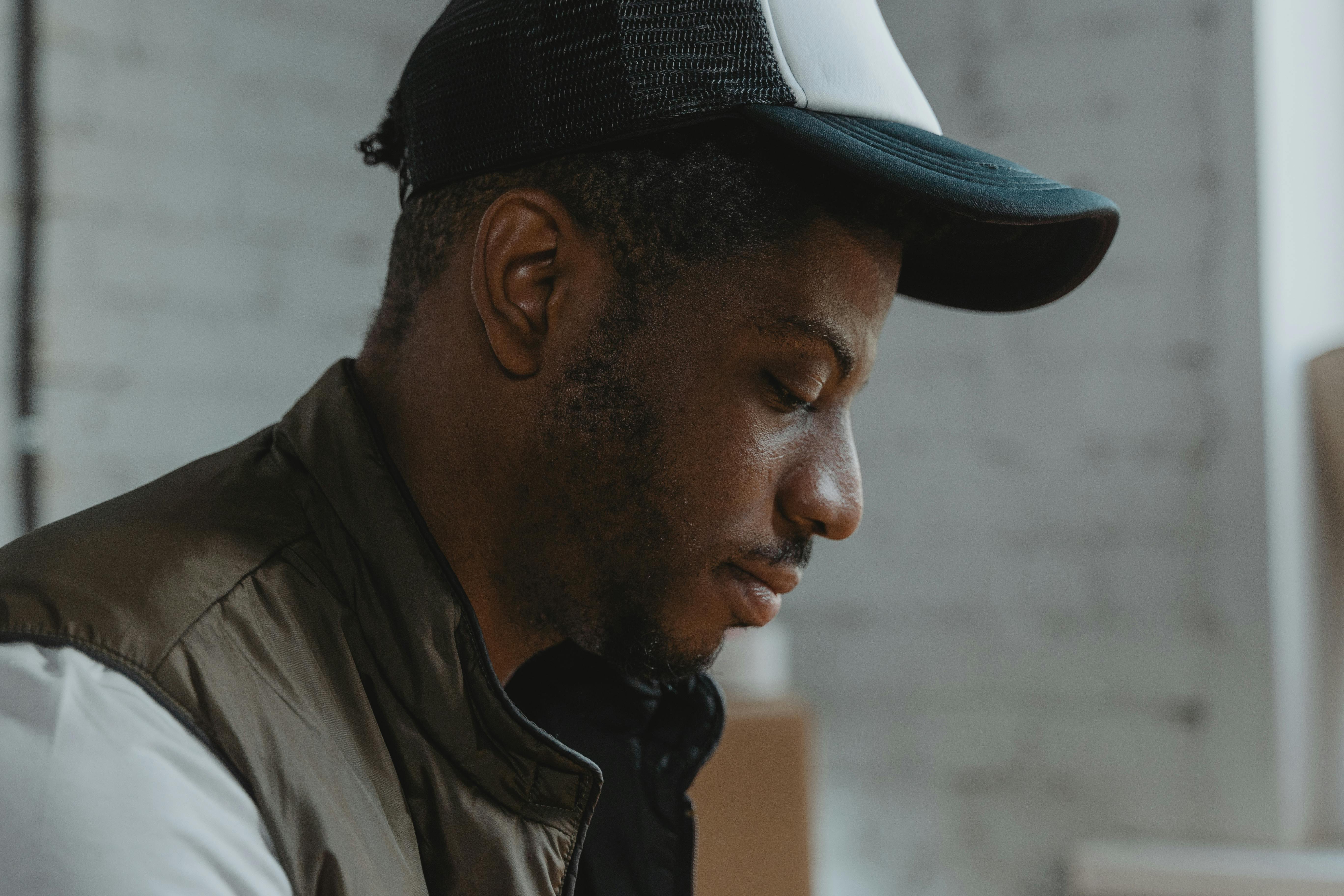 Close-up side profile of a thoughtful man wearing a cap indoors, creating a serene and contemplative mood.