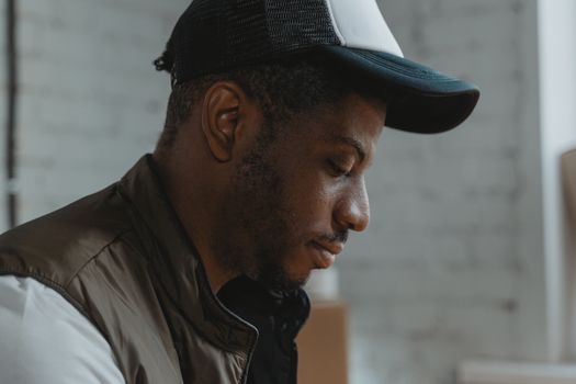 Close-up side profile of a thoughtful man wearing a cap indoors, creating a serene and contemplative mood.