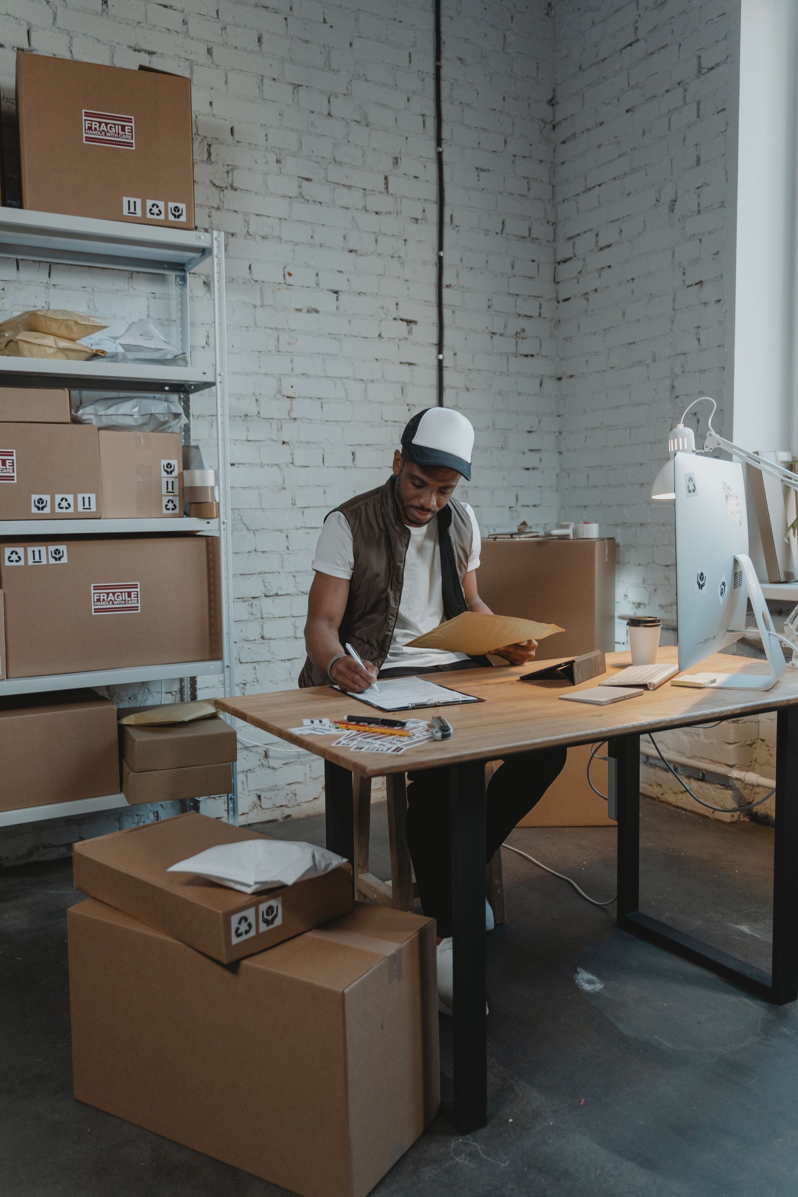 Warehouse employee recording order details on paper among parcels