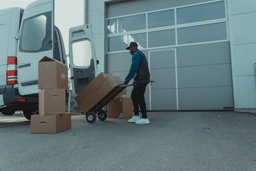 Delivery Man pulling a Trolley with Carton Boxes