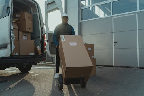 Free Delivery Man pulling a Trolley with Carton Box Stock Photo