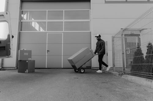 Delivery Man pushing a Trolley with Carton Box