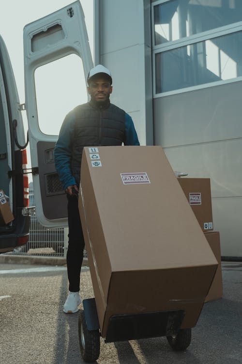 Delivery Man pushing a Trolley with Carton Boxes