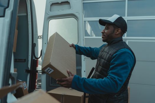Delivery man unloading parcels from van for shipment.