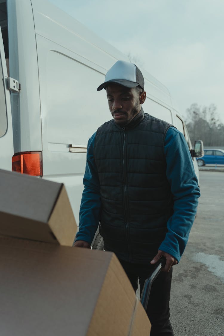 Delivery Man Pushing A Trolley With Carton Boxes