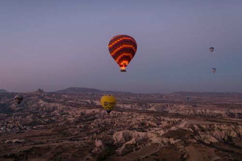 Free Colorful hot air balloons float over the unique Cappadocia landscape at twilight. Stock Photo