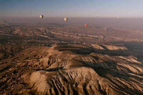 Hot Air Balloons over Brown Rocky Mountains