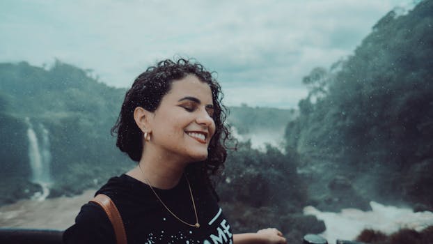 在薄雾缭绕的瀑布附近，一位妇女微笑着闭上了眼睛