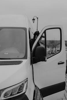 Monochrome image of a delivery driver stepping out of a van.